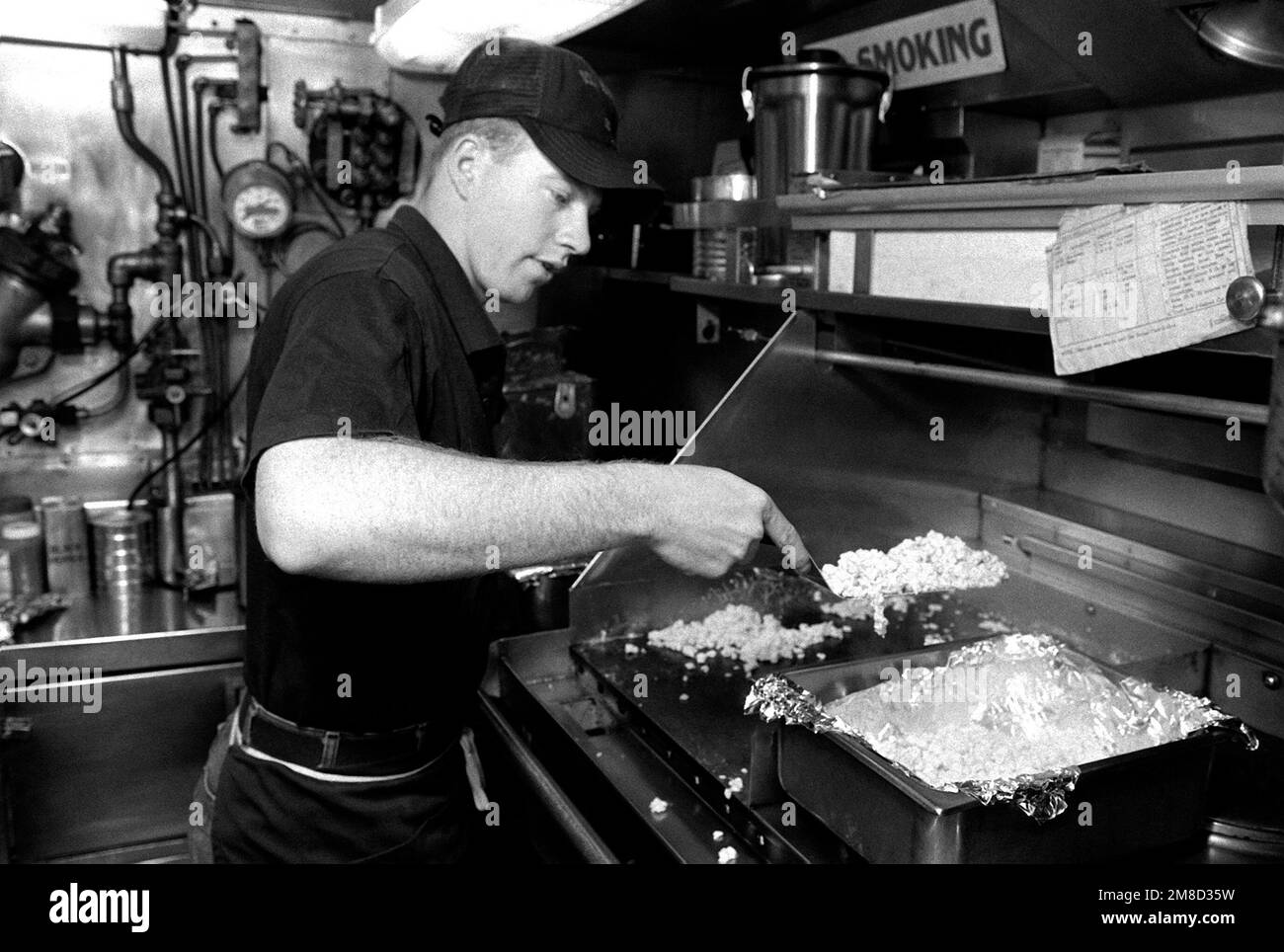 Un esperto di gestione dei disordine prepara uova strapazzate nella cucina a bordo del sottomarino d'attacco USS BLUEBACK (SS-581). Il BLUEBACK, un sottomarino diesel-elettrico, è previsto per lo smantellamento dopo più di 30 anni di servizio attivo. Base: Naval Air Station, San Diego Stato: California (CA) Paese: Stati Uniti d'America (USA) Foto Stock