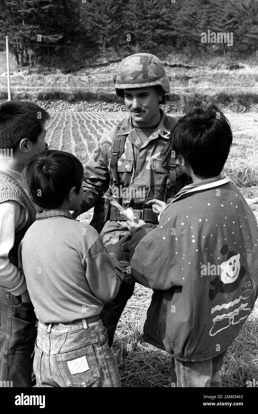 Un corporale marino dà ad alcuni bambini coreani un pacchetto dalle sue razioni di campo durante il sud coreano Unito / US Esercitazione Team Spirit '90. Soggetto operativo/Serie: TEAM SPIRIT '90 Paese: Repubblica di Corea (KOR) Foto Stock