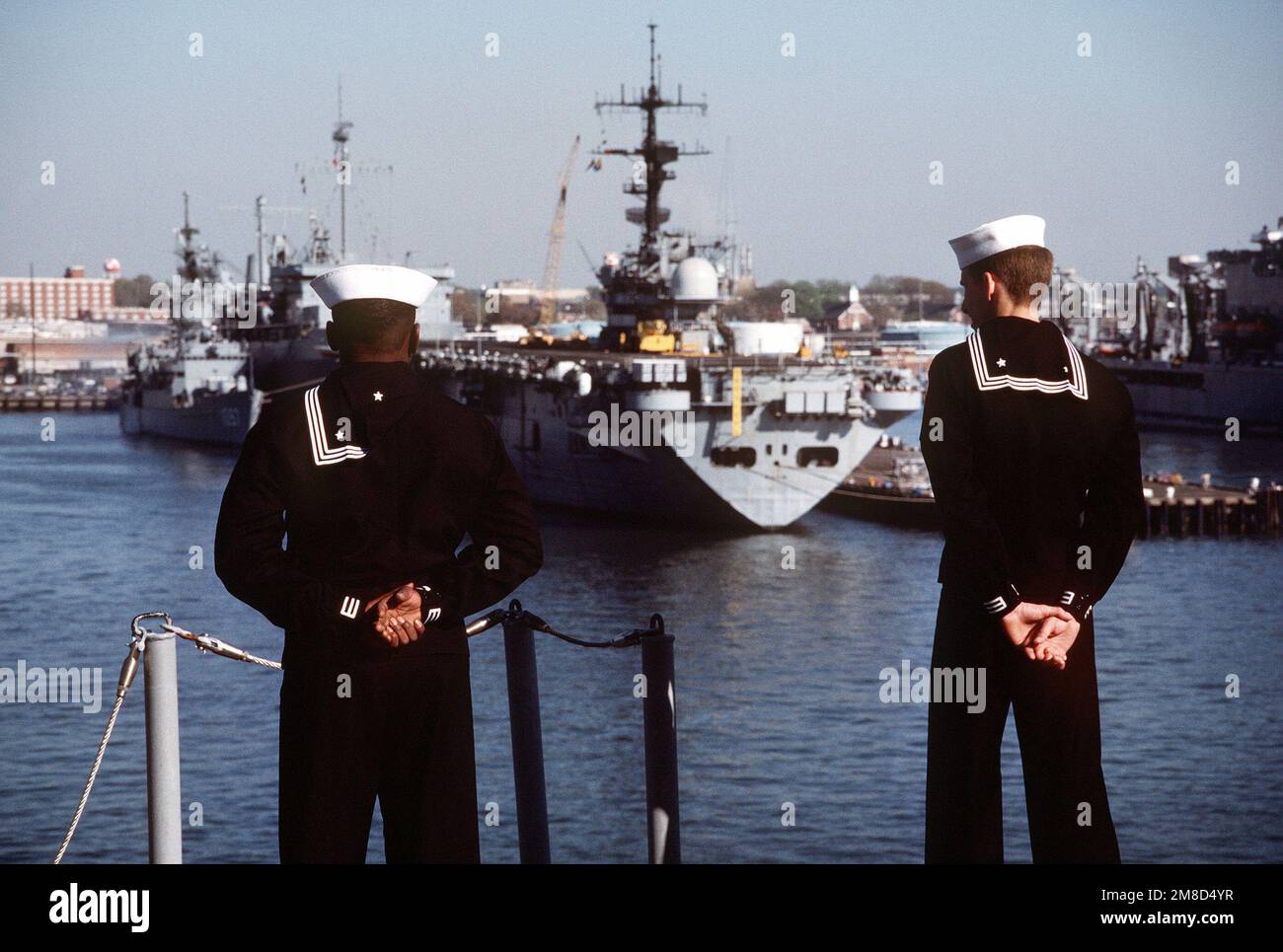 I marinai si imbarcano a bordo della nave d'assalto anfibia USS WASP (LHD-1) mentre la nave passa un'altra nave d'assalto anfibia al suo ingresso nel porto. Base: Naval Station, Norfolk Stato: Virginia (VA) Paese: Stati Uniti d'America (USA) Foto Stock