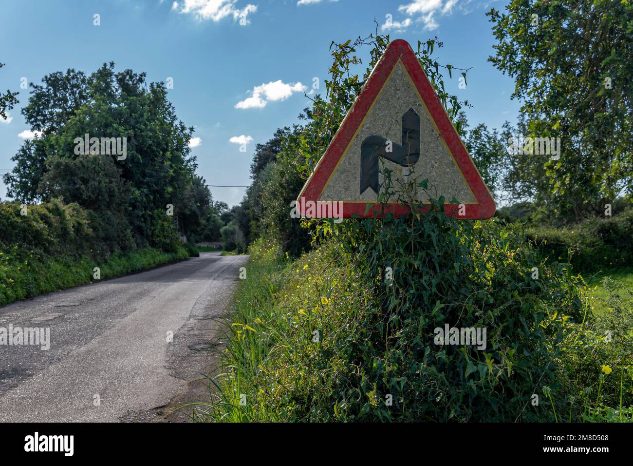Pericolosa curva di segno circondato da torrenti selvaggi su una strada rurale sull'isola di Maiorca, Spagna Foto Stock
