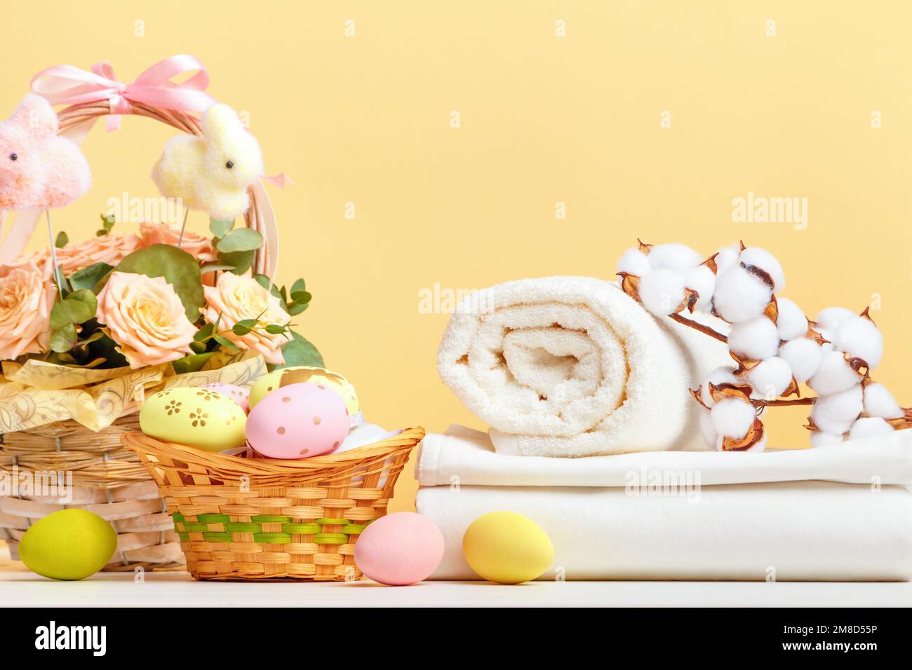 Una pila di lenzuola bianche e rotoli di asciugamani con decorazioni pasquali sul tavolo. Spazio di copia di vita di fermo Foto Stock