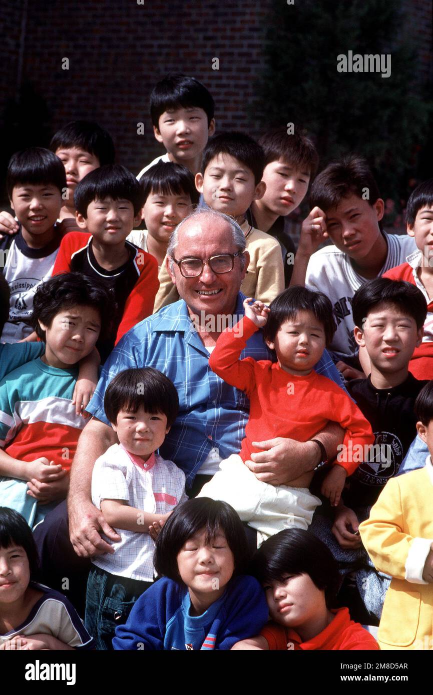 I bambini amerasiani circondano Padre Bernard Zweber, direttore del St Vincent è la casa degli Amerasiani. Il capitolo della Osan Air base della Amerasian Children's Society è un importante sostenitore dell'orfanotrofio per la prole delle donne coreane e dei militari americani da lungo tempo assenti. Paese: Repubblica di Corea (KOR) Foto Stock