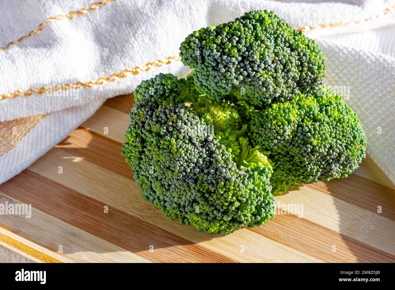 Broccoli grezzi biologici e luminosi sul tavolo in primo piano in cucina. Foto Stock
