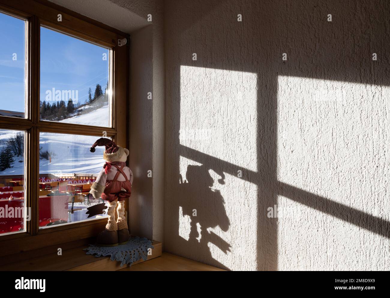 La luce del sole penetra attraverso una finestra che si affaccia su una pista da sci, Austria Foto Stock