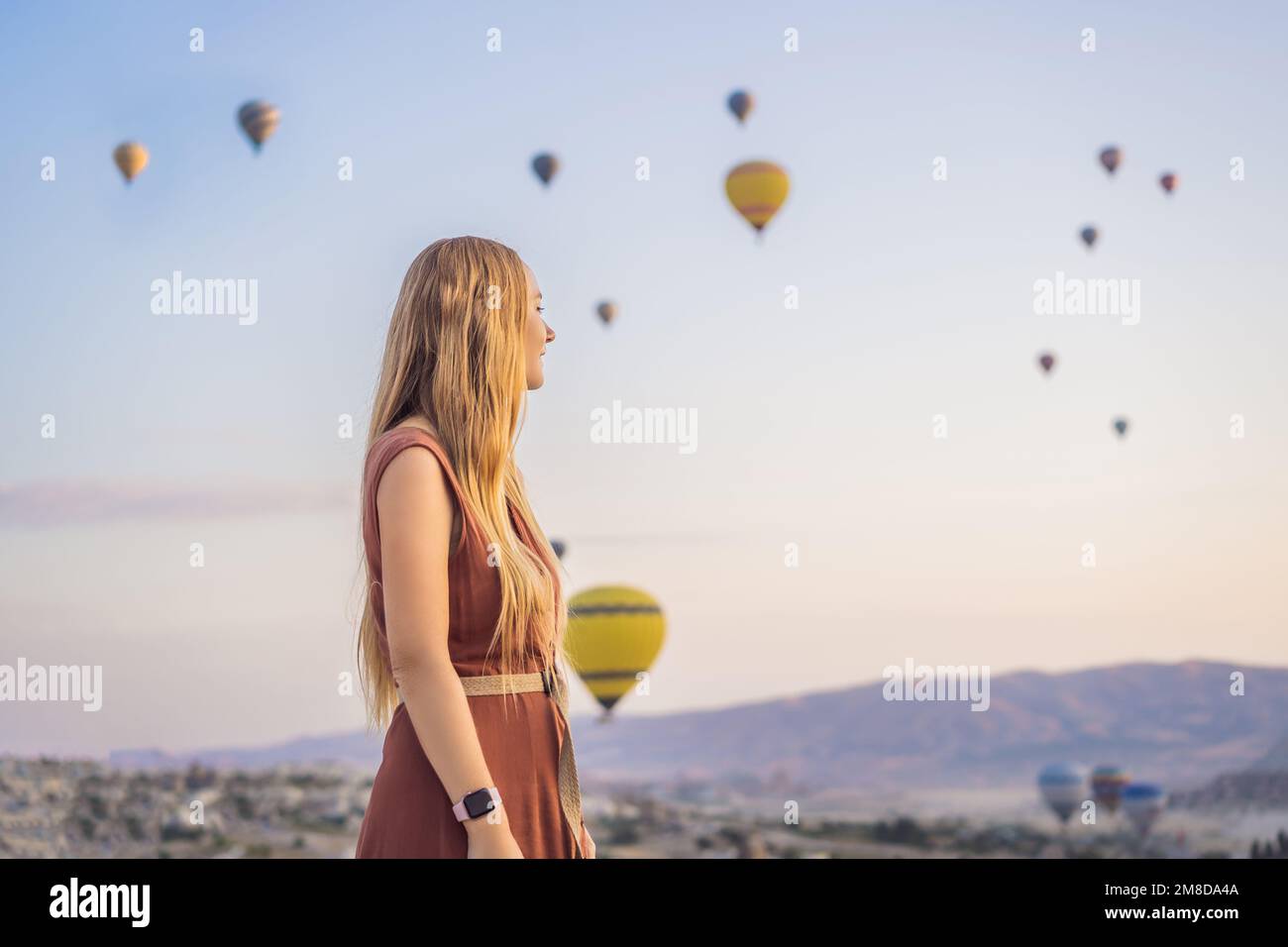 Donna turistica che guarda mongolfiere in Cappadocia, Turchia. Buon viaggio in Turchia concetto. Donna in cima a una montagna che gode di una vista meravigliosa Foto Stock