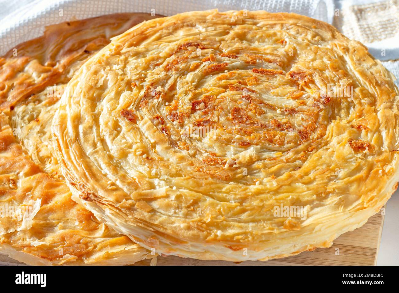 Tradizionale Tajik Fatir fatto in casa (pane piatto a strati) con formaggio e cipolla su sfondo di legno chiaro primo piano. Foto Stock