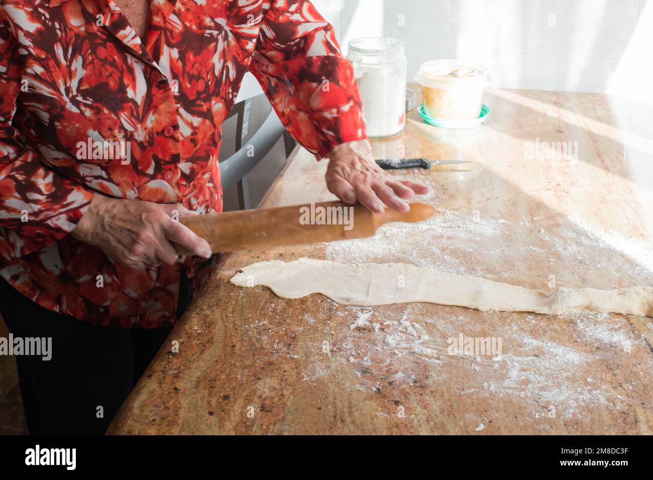 Donna irriconoscibile mani con un perno di rotolamento preparare casadielles riempito di noci a casa. Gastronomia tradizionale Foto Stock
