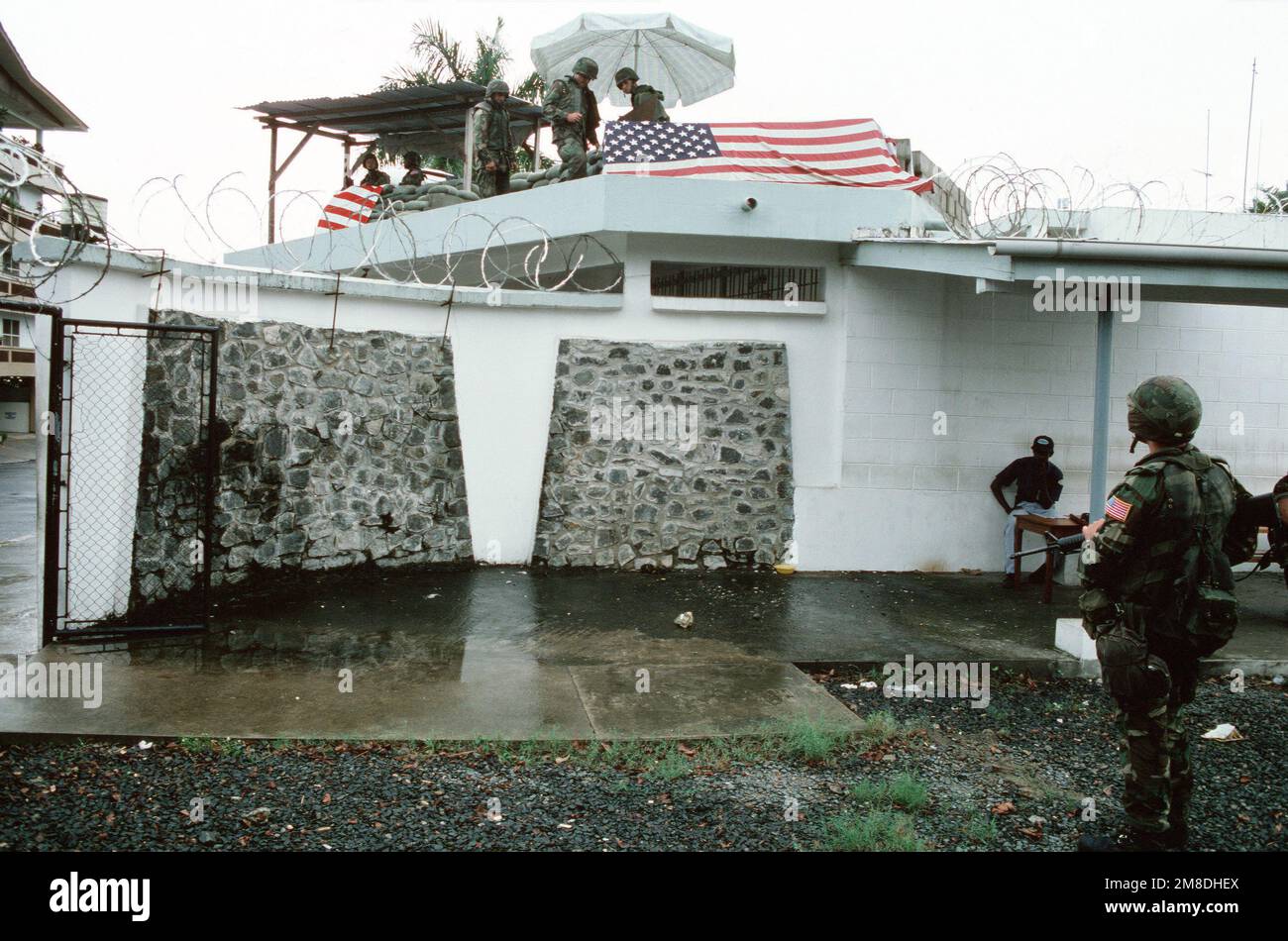 NEGLI STATI UNITI Marine stand guardia come i suoi compagni costruire un rifugio di sandbag in cima a una sezione dell'Ambasciata americana durante l'operazione TAGLIENTE BORDO. I marines sono all'ambasciata per aiutare nell'evacuazione del personale durante i disordini politici in corso in Liberia. Subject Operation/Series: SHARP EDGE base: Monrovia Nazione: Liberia (LBR) Foto Stock
