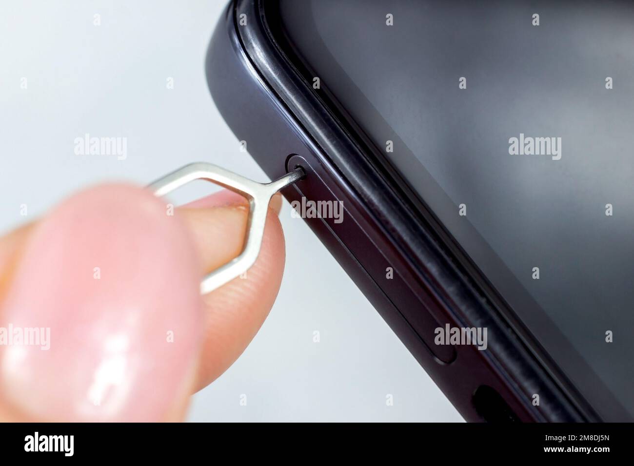 Donna che estrae l'alloggiamento della scheda sim del telefono dallo smartphone con l'aiuto di Edgector da vicino. Foto Stock