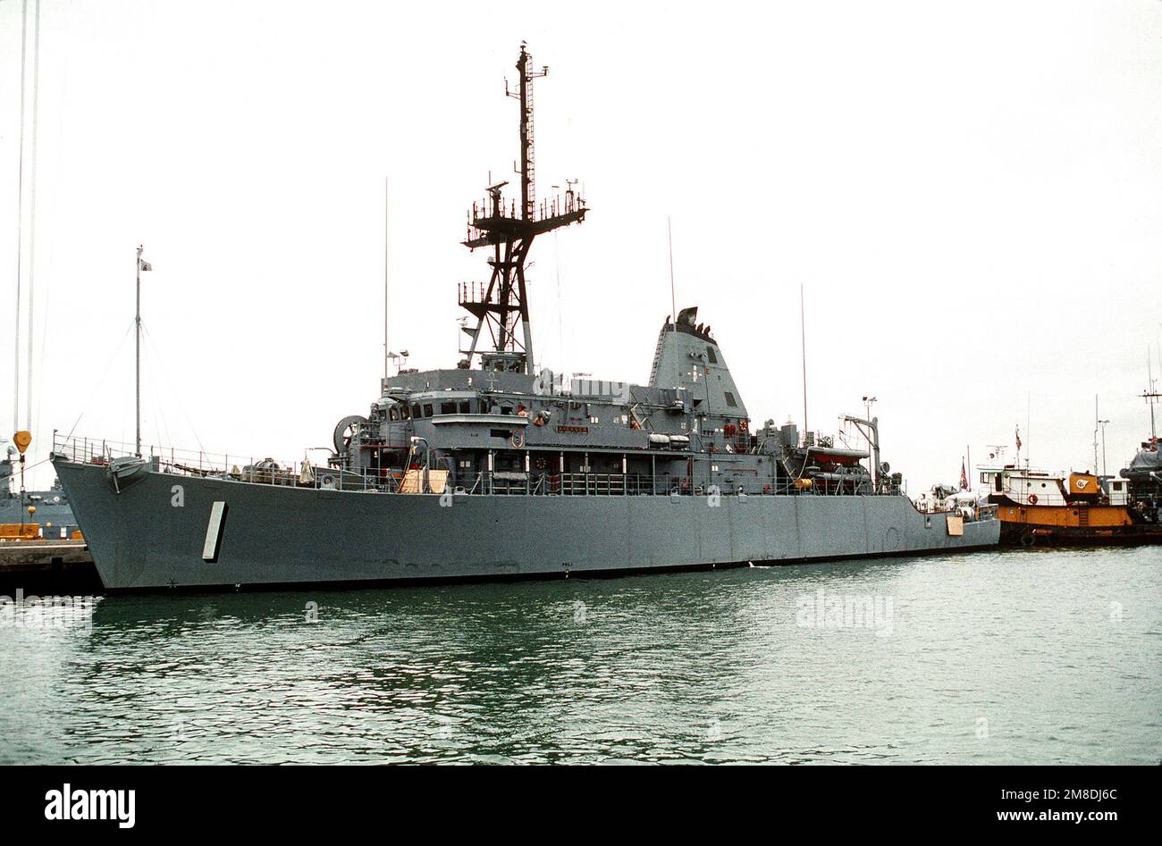 Un rimorchiatore si sposta in posizione a poppa della USS AVENGER (CMC-1) mentre si preparano per caricare la nave di contromisura della miniera a bordo della nave a sollevamento pesante olandese SUPER SERVER 3. Il SUPER SERVITORE 3 trasporterà ADORABILI e altri minatori nel Golfo Persico in risposta all'invasione del Kuwait da parte dell'Iraq. Soggetto operativo/Serie: DESERT SHIELD/STORM base: Naval Air Station, Norfolk Stato: Virginia (VA) Paese: Stati Uniti d'America (USA) Foto Stock