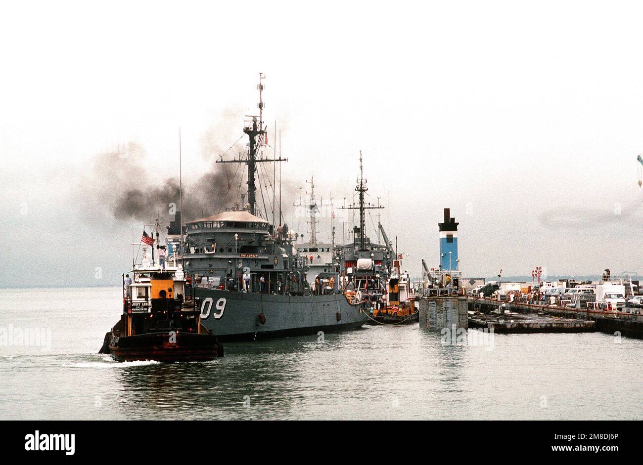 Un rimorchiatore posiziona il minesweeper dell'oceano USS ADROIT (MSO-509) sul ponte sommerso della nave pesante olandese SUPER SERVER 3. Il SUPER SERVITORE 3 trasporterà ADORABILI e altri minatori nel Golfo Persico in risposta all'invasione del Kuwait da parte dell'Iraq. Soggetto operativo/Serie: DESERT SHIELD/STORM base: Naval Air Station, Norfolk Stato: Virginia (VA) Paese: Stati Uniti d'America (USA) Foto Stock