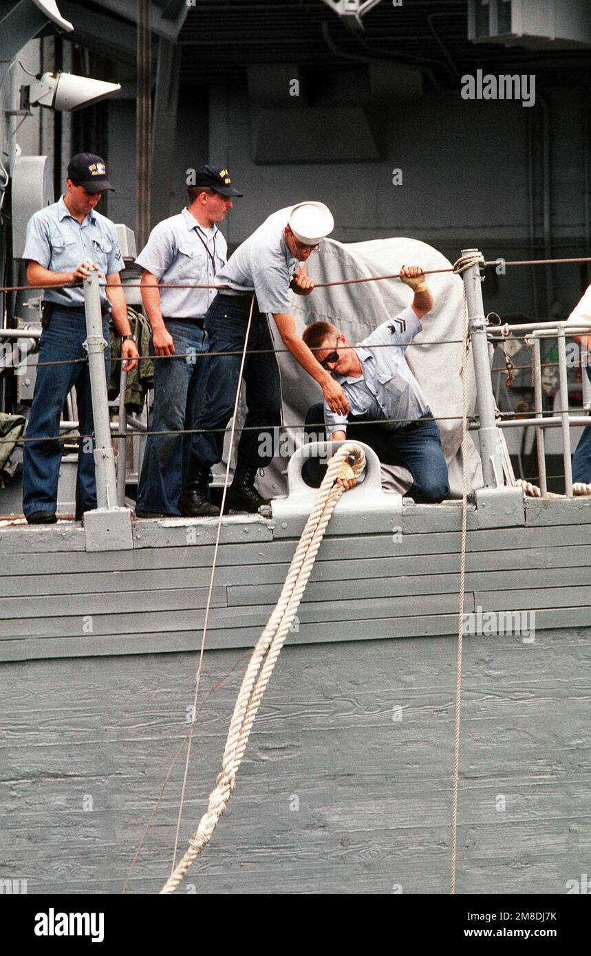 I membri dell'equipaggio tirano una linea di ormeggio attraverso un cuneo sulla USS ADROIT (MSO-509) mentre si preparano per caricare il minatore dell'oceano a bordo della nave pesante olandese SUPER SERVER 3. Il SUPER SERVITORE 3 trasporterà ADORABILI e altri minatori nel Golfo Persico in risposta all'invasione del Kuwait da parte dell'Iraq. Soggetto operativo/Serie: DESERT SHIELD/STORM base: Naval Air Station, Norfolk Stato: Virginia (VA) Paese: Stati Uniti d'America (USA) Foto Stock
