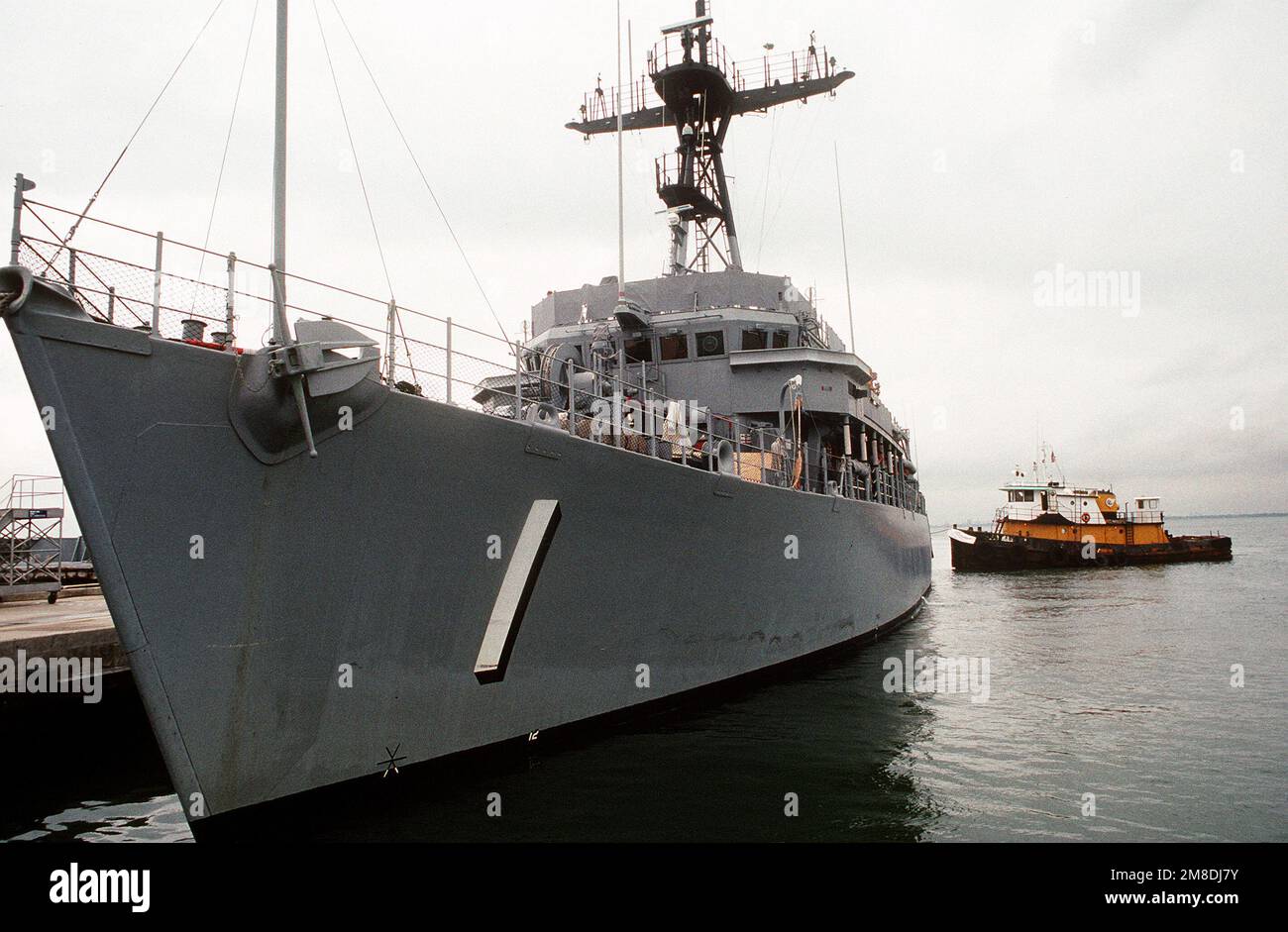 Un rimorchiatore allontana la USS AVENGER (MCM-1) da un molo mentre si preparano per caricare la nave di contromisura della miniera a bordo della nave pesante Super SERVER 3 olandese. Il SUPER SERVITORE 3 trasporterà ADORABILI e altri minatori nel Golfo Persico in risposta all'invasione del Kuwait da parte dell'Iraq. Soggetto operativo/Serie: DESERT SHIELD/STORM base: Naval Air Station, Norfolk Stato: Virginia (VA) Paese: Stati Uniti d'America (USA) Foto Stock