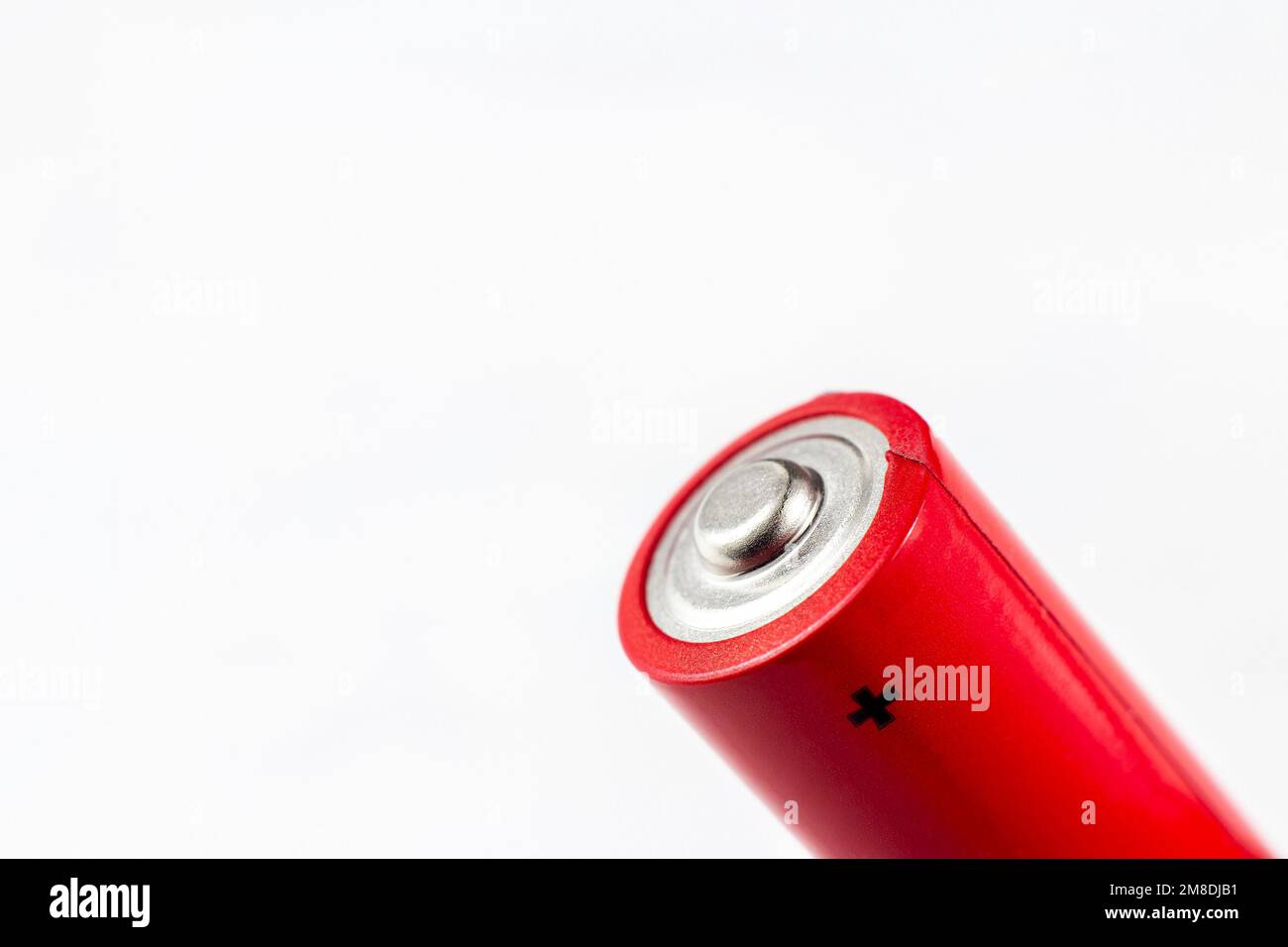 Batteria aa alcalina in metallo rosso brillante con segno più su sfondo chiaro primo piano con spazio di copia. Foto Stock