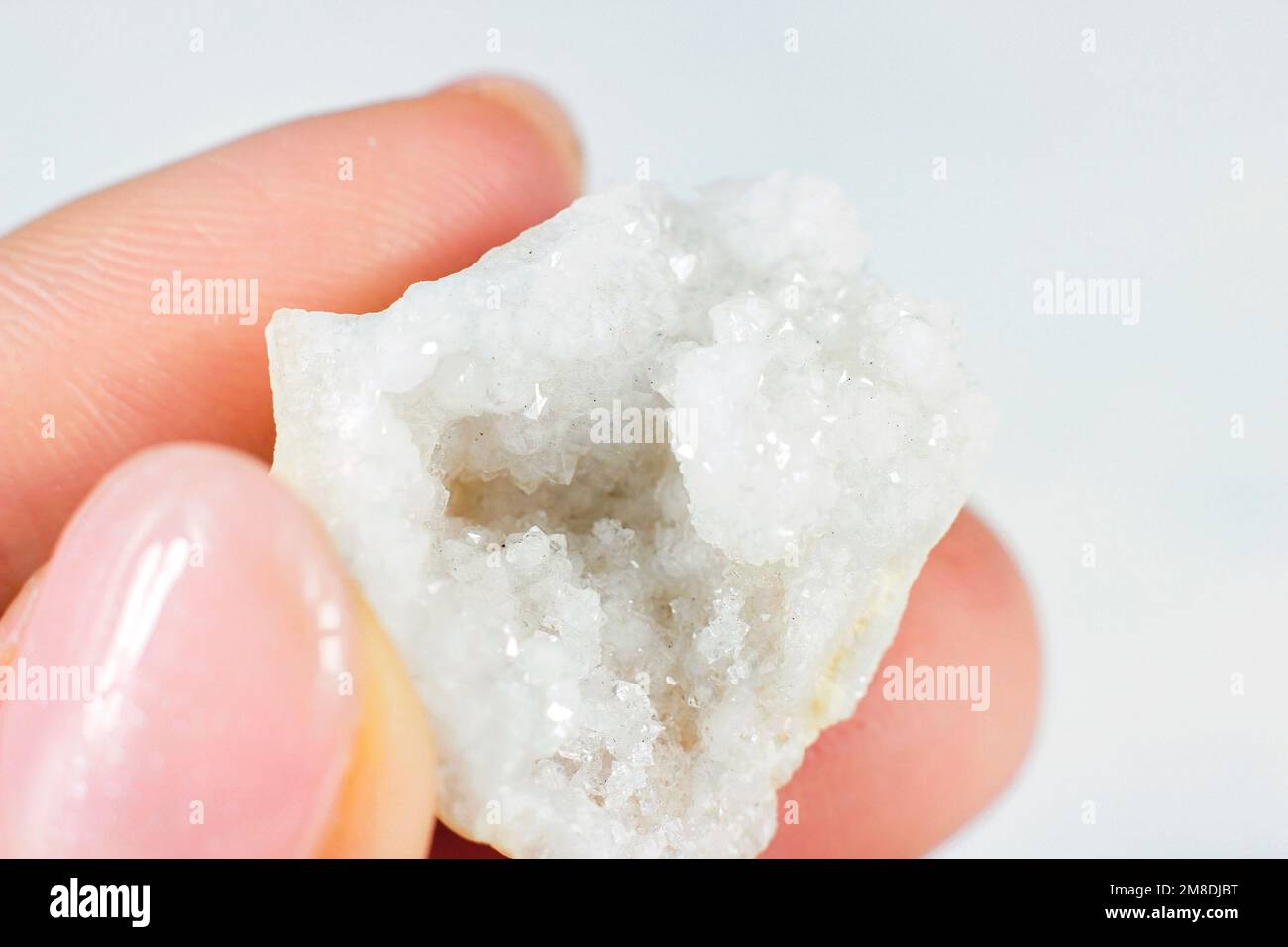 Donna che tiene bianco lucido cristallo Agata su sfondo chiaro primo piano. Foto Stock