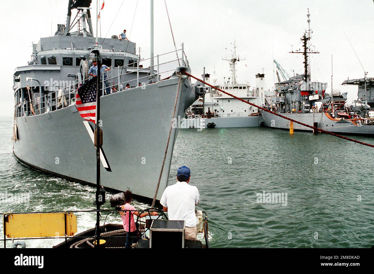 Un rimorchiatore sposta la nave USS AVENGER (MCM-1) sul ponte sommerso della nave a sollevamento pesante olandese SUPER SERVER 3. Il LEADER della USS (MSO-490) è sulla destra. Il VENDICATORE, il leader e altri due minatori oceanici sono stati caricati a bordo del SUPER SERVITORE 3 per il trasporto al Golfo Persico, dove sosterranno le forze degli Stati Uniti inviate nella regione in risposta all'invasione dell'Iraq del Kuwait. Soggetto operativo/Serie: DESERT SHIELD/STORM base: Naval Air Station, Norfolk Stato: Virginia (VA) Paese: Stati Uniti d'America (USA) Foto Stock
