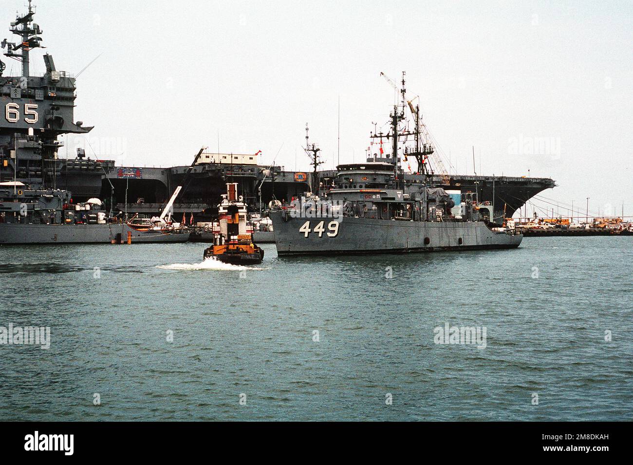 Il minesweeper oceanico USS IMPERVIO (MSO-449) è spostato in posizione sul ponte sommerso della nave pesante olandese SUPER SERVER 3. Tre Stati Uniti I minesweepers dell'oceano della Marina e una nave di contromisure della miniera stanno caricando a bordo del SUPER SERVITORE 3 per il trasporto al golfo persiano, dove sosterranno le forze degli Stati Uniti inviate nella regione in reazione all'invasione dell'Iraq del Kuwait. La portaerei a energia nucleare USS ENTERPRISE (CVN-65) è in secondo piano. Soggetto operativo/Serie: DESERT SHIELD/STORM base: Naval Air Station, Norfolk Stato: Virginia (VA) Paese: Stati Uniti di Ame Foto Stock