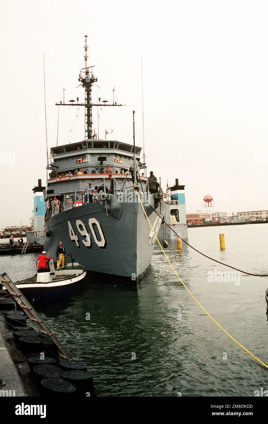 Gli equipaggi a bordo del LEADER USS (MSO-490) sono in attesa mentre la loro nave viene spostata in posizione sul ponte della nave pesante olandese SUPER SERVER 3. Tre Stati Uniti I minesweepers dell'oceano della Marina e una nave di contromisure della miniera stanno caricando a bordo del SUPER SERVITORE 3 per il trasporto al golfo persiano, dove sosterranno le forze degli Stati Uniti inviate nella regione in reazione all'invasione dell'Iraq del Kuwait. La portaerei a energia nucleare USS ENTERPRISE (CVN-65) è in secondo piano. Soggetto operativo/Serie: DESERT SHIELD/STORM base: Naval Air Station, Norfolk Stato: Virginia (VA) Conte Foto Stock