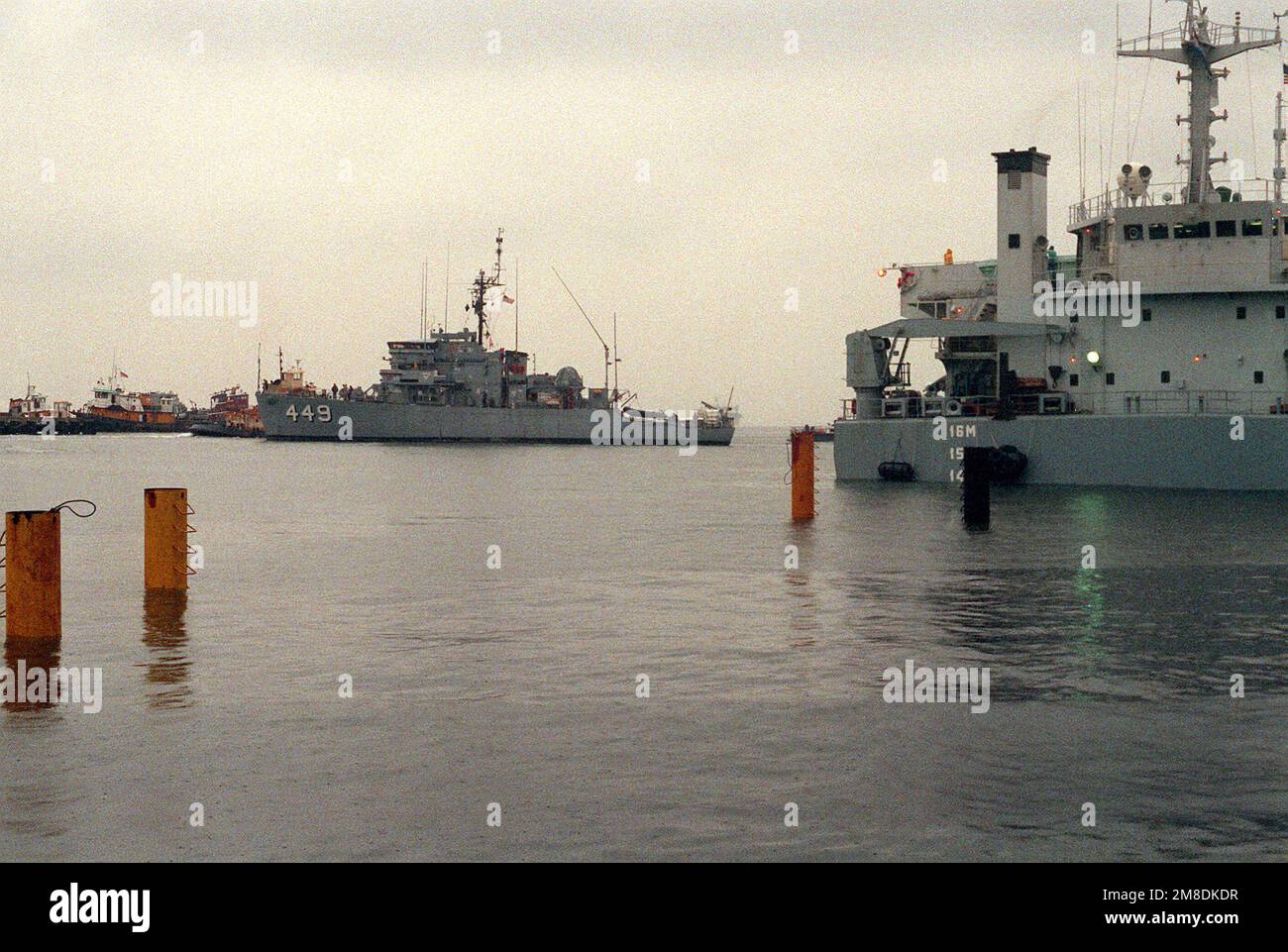 Le barche di rimorchiatore si muovono per guidare il minesweeper dell'oceano USS IMPERVIO (MSO-449) sopra il ponte sommerso della nave pesante olandese Super SERVER 3. La sovrastruttura del Super Servant 3 è a destra. Il SUPER SERVITORE 3 porterà l'IMPERVIO, due altri minatori oceanici e una nave di contromisure mine al Golfo Persico, dove le forze statunitensi stanno operando in risposta all'invasione del Kuwait da parte dell'Iraq. Base: Naval Air Station, Norfolk Stato: Virginia (VA) Paese: Stati Uniti d'America (USA) Foto Stock