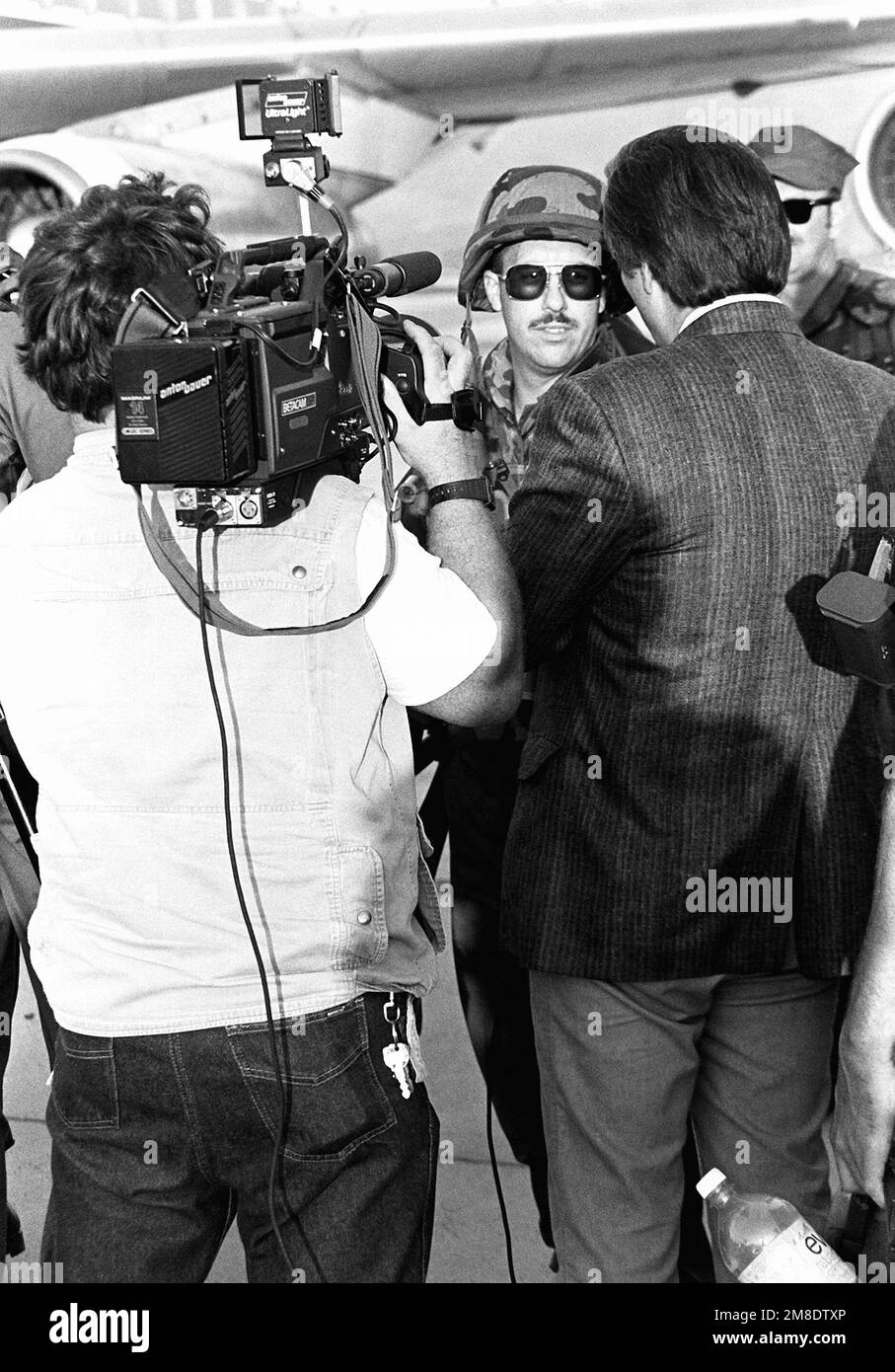 Un equipaggio di una stazione televisiva locale intervista un Seabee della Naval Mobile Construction Battalion 5 (NMCB-5) mentre si prepara a bordo di un aereo di linea noleggiato. Centosessantadue membri della NMCB-5 stanno volando in Arabia Saudita per partecipare all'operazione Desert Shield. Soggetto operativo/Serie: BASE DELLO SCUDO DEL DESERTO: Base aerea navale, Point Mugu Stato: California (CA) Paese: Stati Uniti d'America (USA) Foto Stock