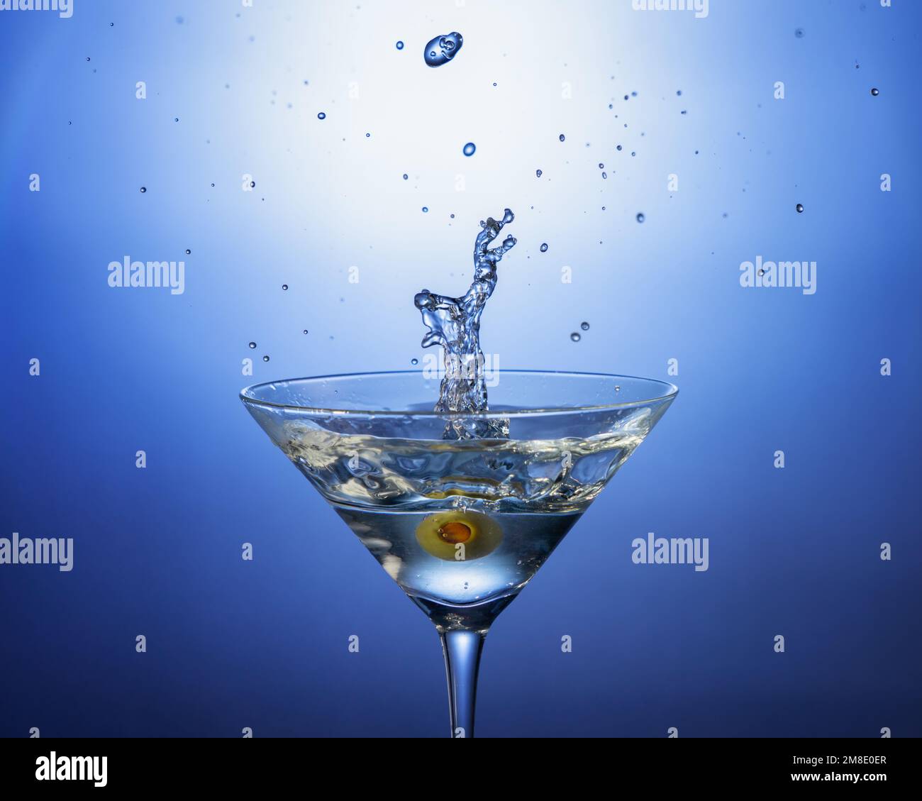 Una foto da cocktail di un'oliva è caduta in un martini sporco. Ripresa con illuminazione da studio e strobo di sincronizzazione ad alta velocità. Ideale per menu, Web o pubblicazioni Foto Stock