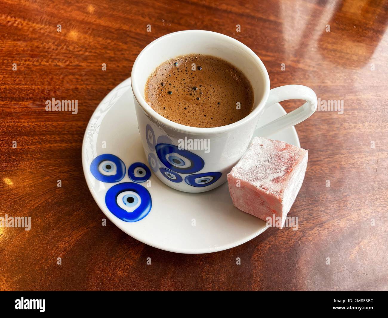 Tradizionale tazza di caffè turco su piatto, e delizia turco lokum su un tavolo di legno marrone. Simbolo blu turco occhio nazar su una tazza di porcellana e piatto Foto Stock