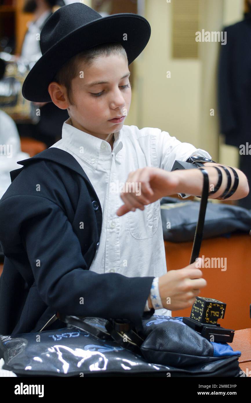 Un giovane ebreo che si avvicina al suo Bar Mitzvah mette sul tefillin. È un'usanza di Chabad metterli presto sopra per essere un esperto all'età 13. A Brooklyn, . Foto Stock