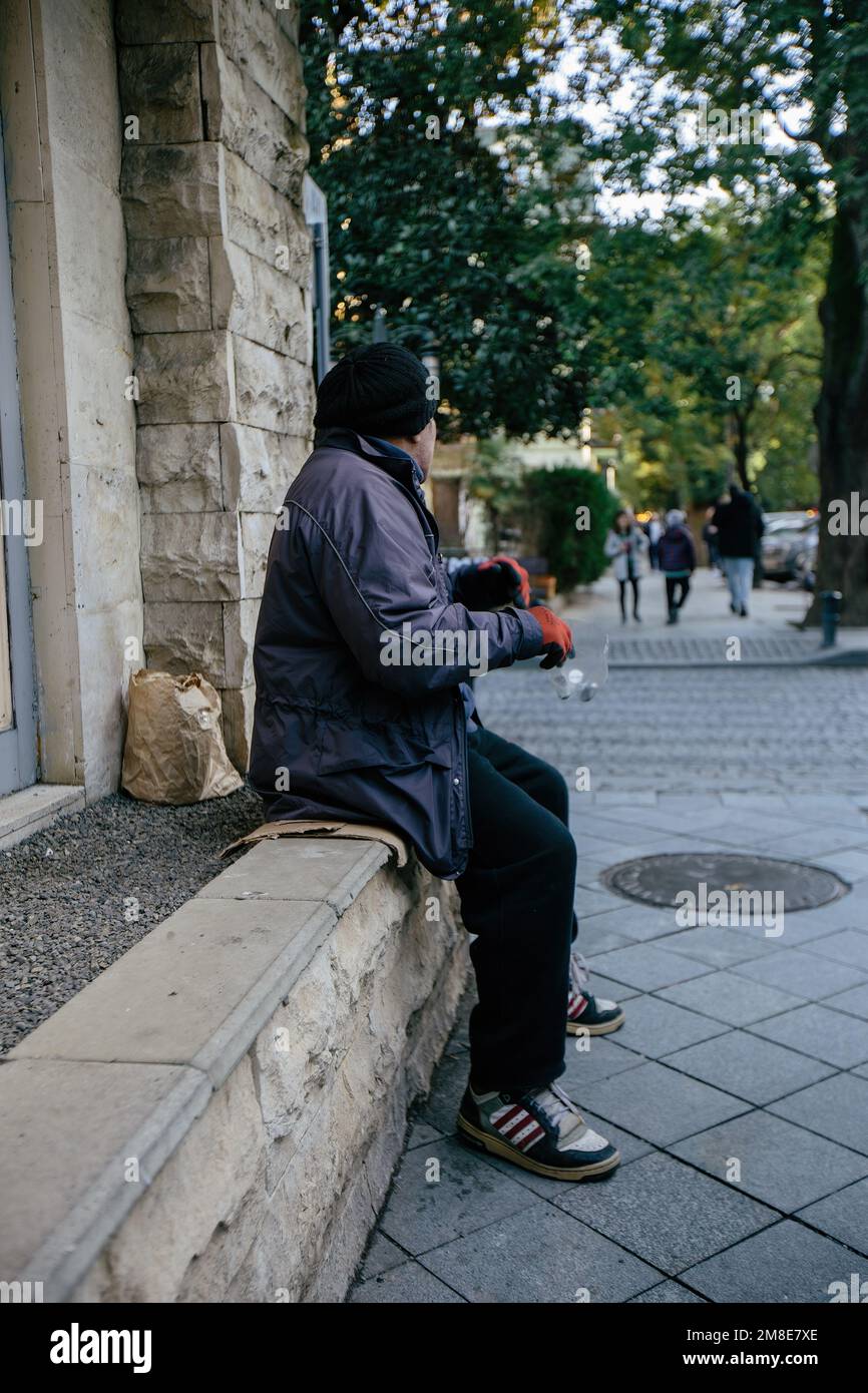 Un triste uomo senza casa chiede denaro per strada. Foto Stock