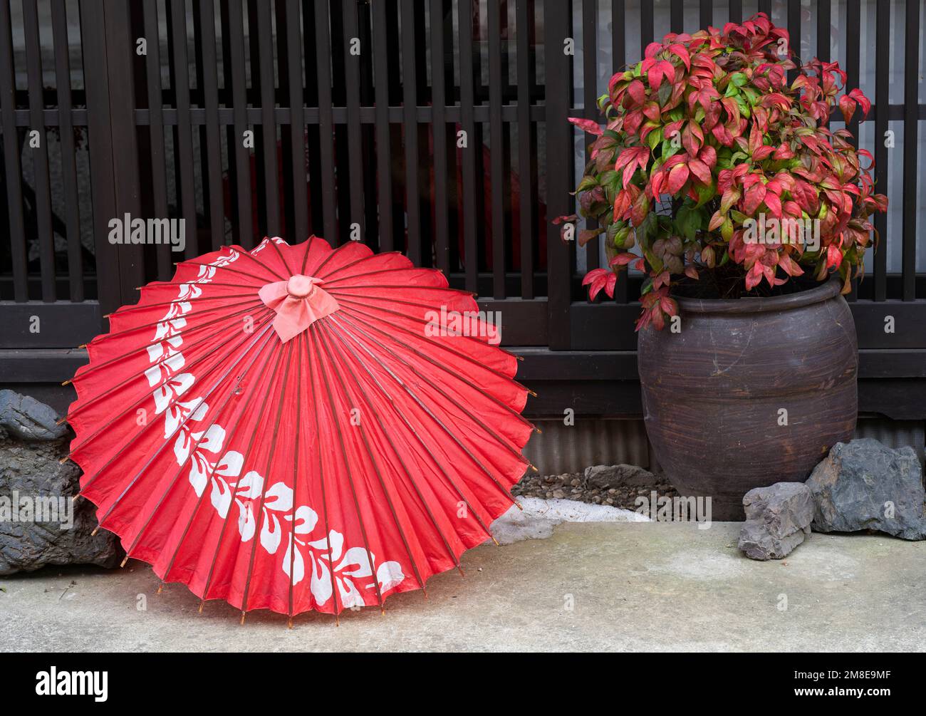 Un ombrellone rosso e una pianta a Narai-juku, un quartiere conservato sulla strada di Nakasendo a Shiojiri, Prefettura di Nagano, Giappone. Foto Stock