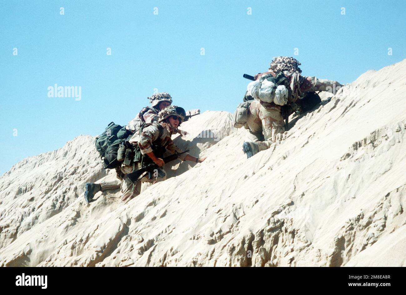 Tre Marines si arrampicano sul lato di un berme mentre si spostano in avanti nelle posizioni di attacco durante la TEMPESTA DEL DESERTO operazione. Soggetto operativo/Serie: TEMPESTA DEL DESERTO Paese: Arabia Saudita (SAU) Foto Stock