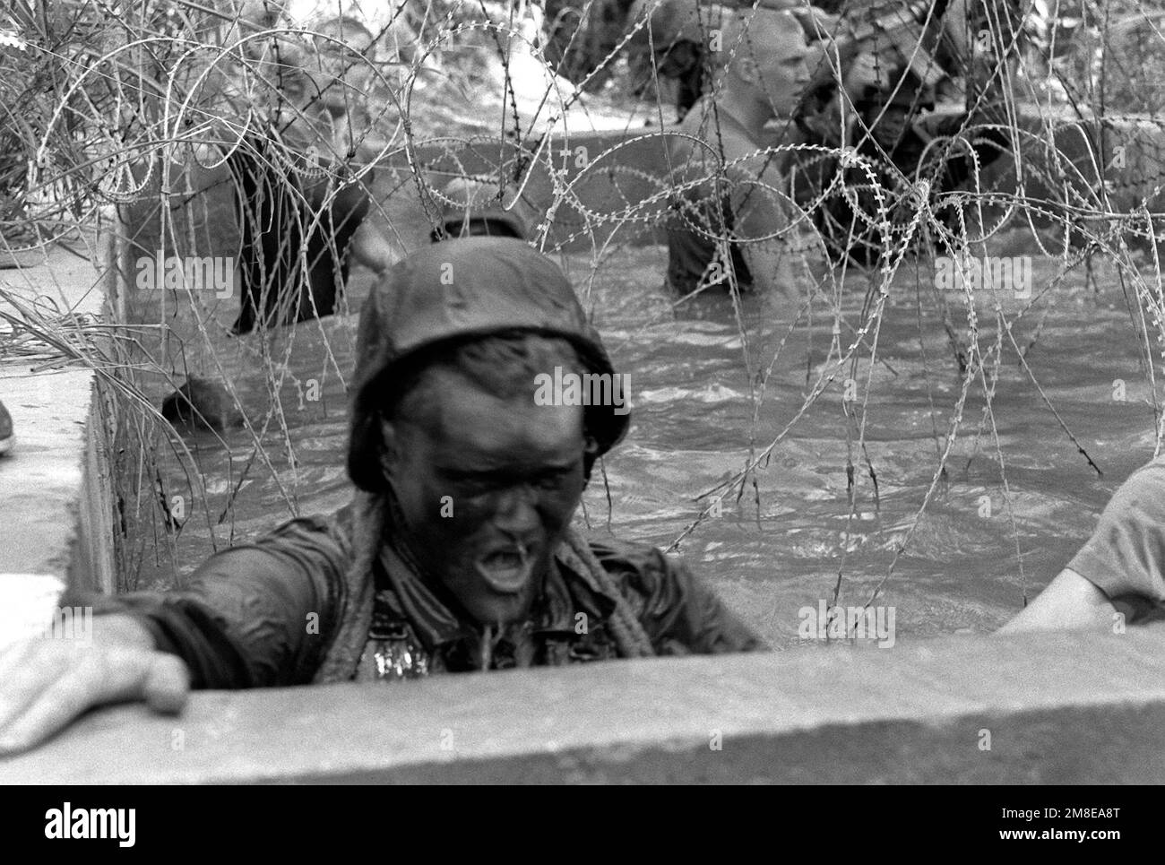 Un membro della Co.. C, 1st BN., 7th Marines, emerge da una fossa piena d'acqua e cosparsa di filo spinato durante una sessione di allenamento. Base: Camp Schwab Paese: Giappone (JPN) Foto Stock