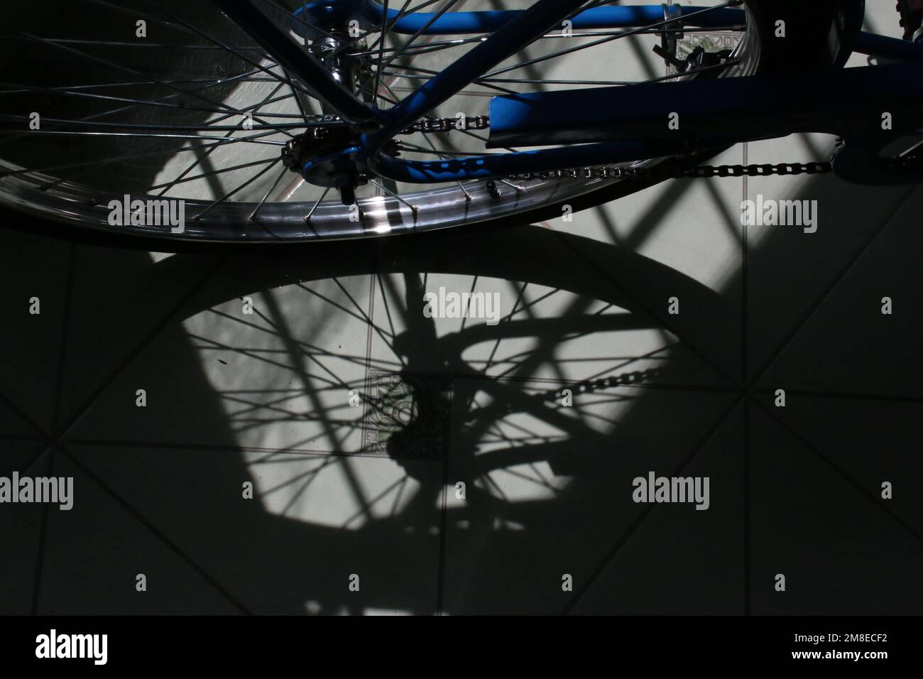 Ombra di fusione dello pneumatico posteriore della bicicletta sul pavimento piastrellato Foto Stock