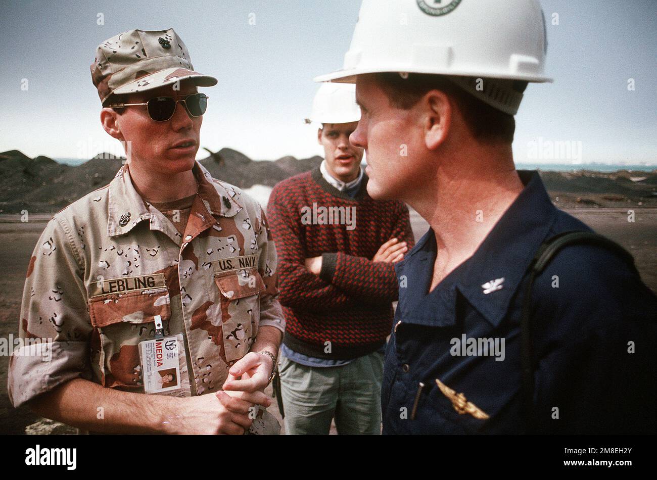 KEITH Lebling, CHIEF PETTY Officer del personale del servizio di radiodiffusione della Marina, conduce un'intervista al CAPT. G.B. McEwen, comandante della nave d'assalto anfibio USS TRIPOLI (LPH-10), mentre la nave si trova in una darsena in attesa di riparazioni. Lo scafo DI TRIPOLI fu danneggiato da una miniera irachena che la nave colpì mentre serviva come piattaforma di sminamento nel Golfo Persico settentrionale il 18 febbraio durante l'operazione Desert Storm. Il TRIPOLI è riuscito a proseguire le operazioni dopo che gli equipaggi di controllo dei danni hanno fermato le alluvioni causate dall'esplosione. Subject Operation/Series: DESERT STORM Paese: Bahrain (BHR) Foto Stock