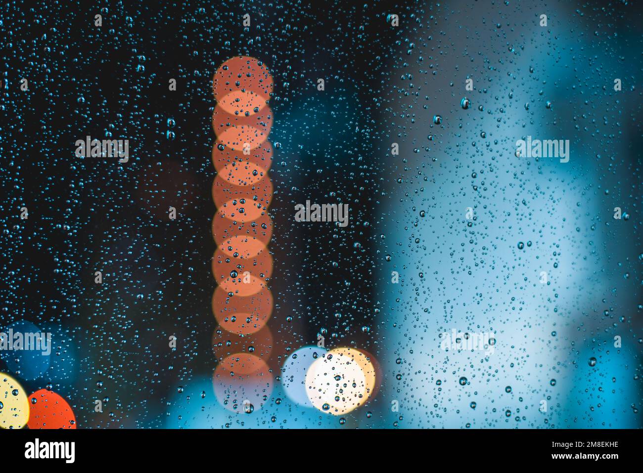 Gocce di pioggia sul parabrezza dell'auto durante la guida notturna in una serata piovosa Foto Stock