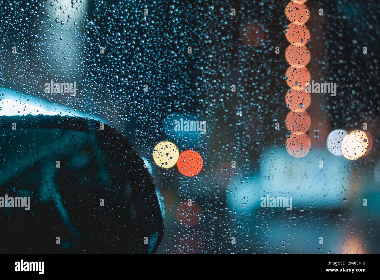 Gocce di pioggia sul parabrezza dell'auto durante la guida notturna in una serata piovosa Foto Stock