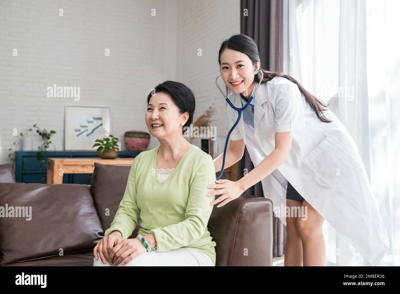 Giovane donna medico per esaminare una donna anziana Foto Stock