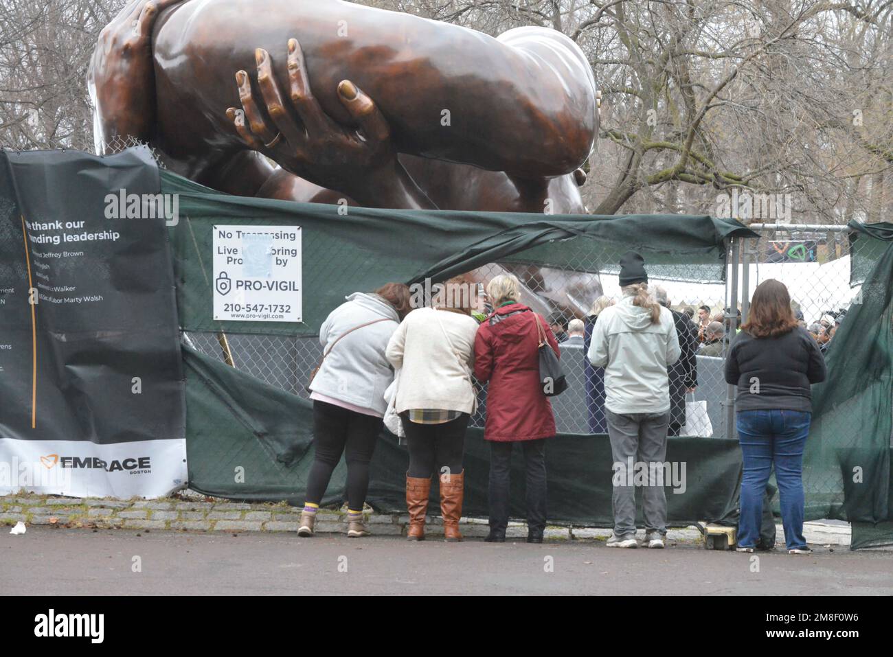 Boston, Massachusetts, Stati Uniti. 14th Jan, 2023. I Botoniani si riuniscono su Boston Common per la presentazione dell'abbraccio, una scultura dedicata alla famiglia Martin Luther re il Re era presente, come lo erano il Governatore Maura Healy e il Sindaco Michelle Wu che faceva discorsi e interacngt con gli invitati. Molti Bostoniani dovevano sollevare tele che copriva la vista che era stata installata su recinzioni a catena per avere un'occhiata alle cerimonie e la statua che poking obiettivi fotocamera attraverso i fori nella recinzione. (Credit Image: © Kenneth Martin/ZUMA Press Wire) SOLO PER USO EDITORIALE! Non per USO commerciale! Foto Stock