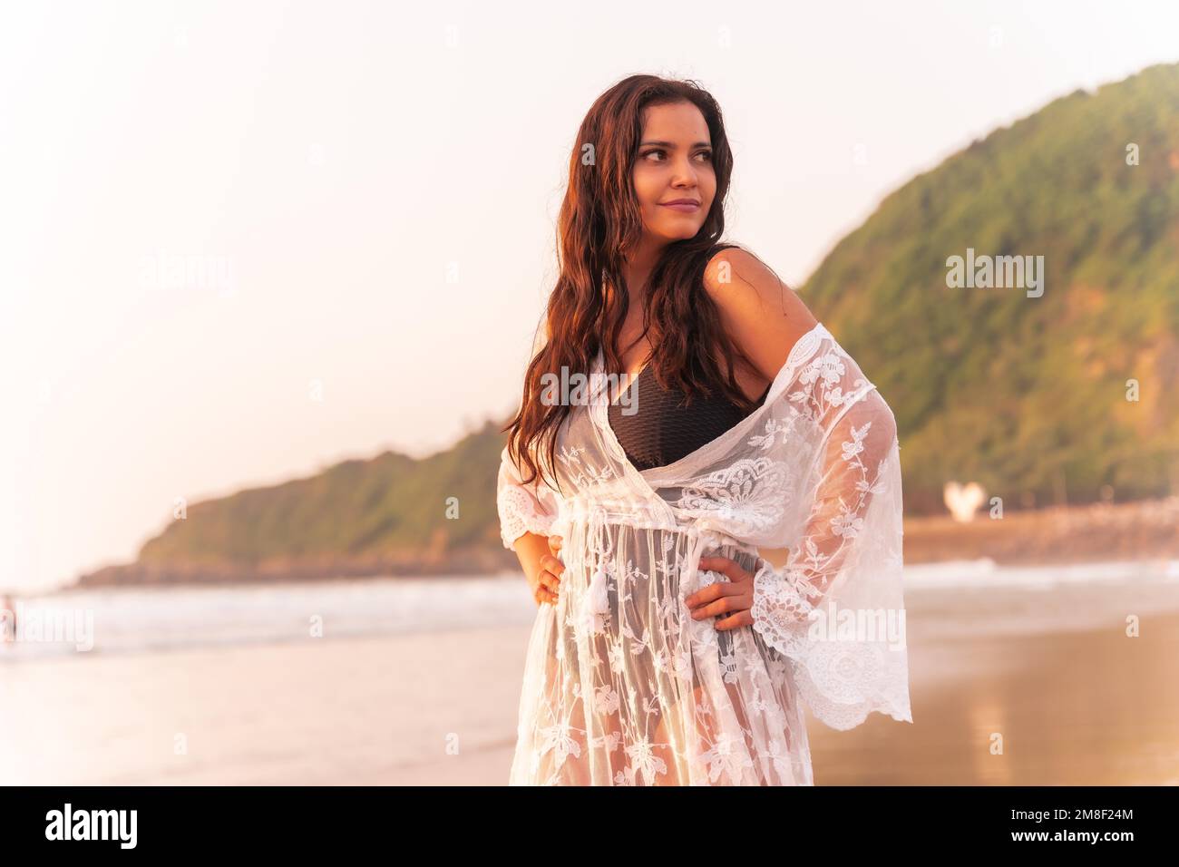 Ritratto di una donna al tramonto in un abito bianco godendo l'estate in spiaggia Foto Stock