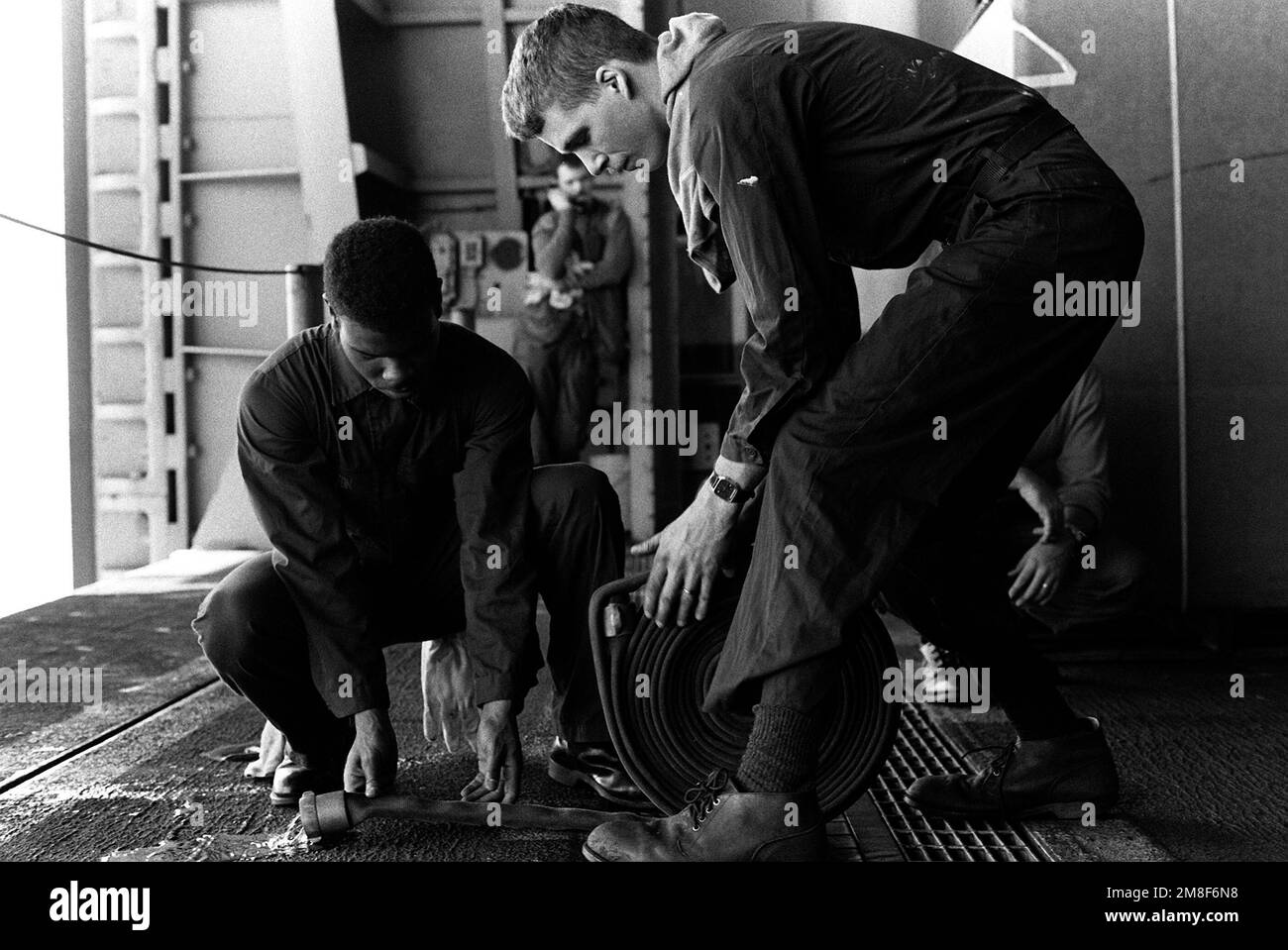 Gli equipanti rotolano un tubo sul ponte della nave d'assalto anfibio USS TRIPOLI (LPH-10). Il TRIPOLI funge da piattaforma per le operazioni di sminamento in elicottero nel Golfo dopo il cessate il fuoco che ha posto fine all'operazione Desert Storm. Soggetto operativo/Serie: DESERT STORM Paese: Sconosciuto Foto Stock