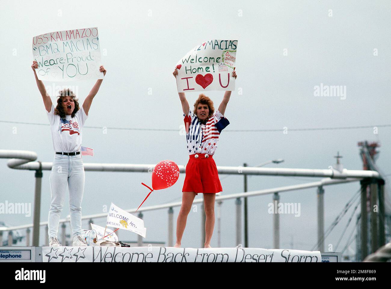 Amici di un marinaio a bordo del rifornito oliatore USS KALAMAZOO (AOR-6) mostra cartelli come la nave ormeggia in porto. L'oliatore è tornato a Norfolk dallo schieramento nell'area del Golfo Persico durante l'operazione Desert Storm. Soggetto operativo/Serie: DESERT STORM base: Naval Air Station, Norfolk Stato: Virginia (VA) Paese: Stati Uniti d'America (USA) Foto Stock