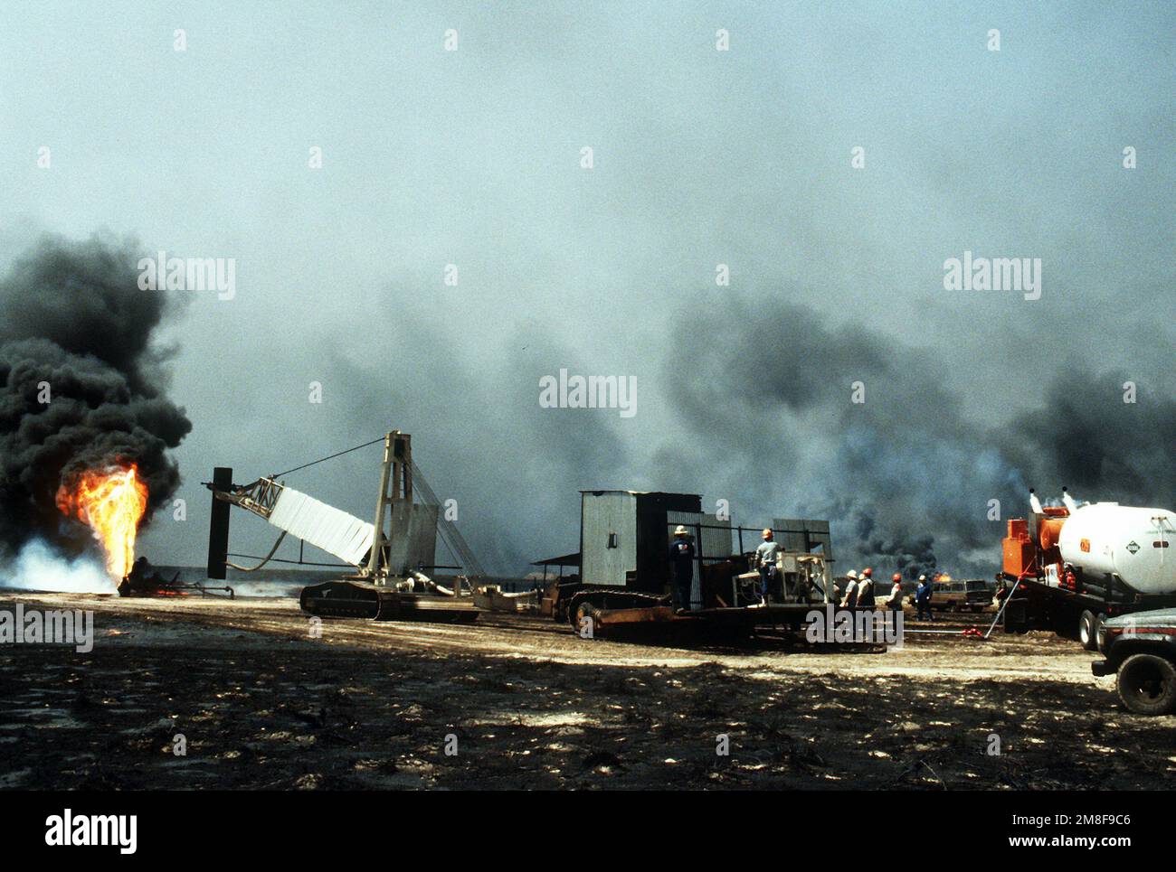 Vigili del fuoco di The Boots and Coots Oil Well Firefighting Company si preparano a posizionare un cappello su un pozzo di fuoco nel periodo successivo a Operation Desert Storm. Il pozzo, situato nei campi di petrolio di Ahman, è uno dei tanti posti in preda alle forze irachene prima del loro ritiro dal Kuwait. Subject Operation/Series: DESERT STORM base: Ahman Oil Fields Paese: Kuwait(KWT) Foto Stock