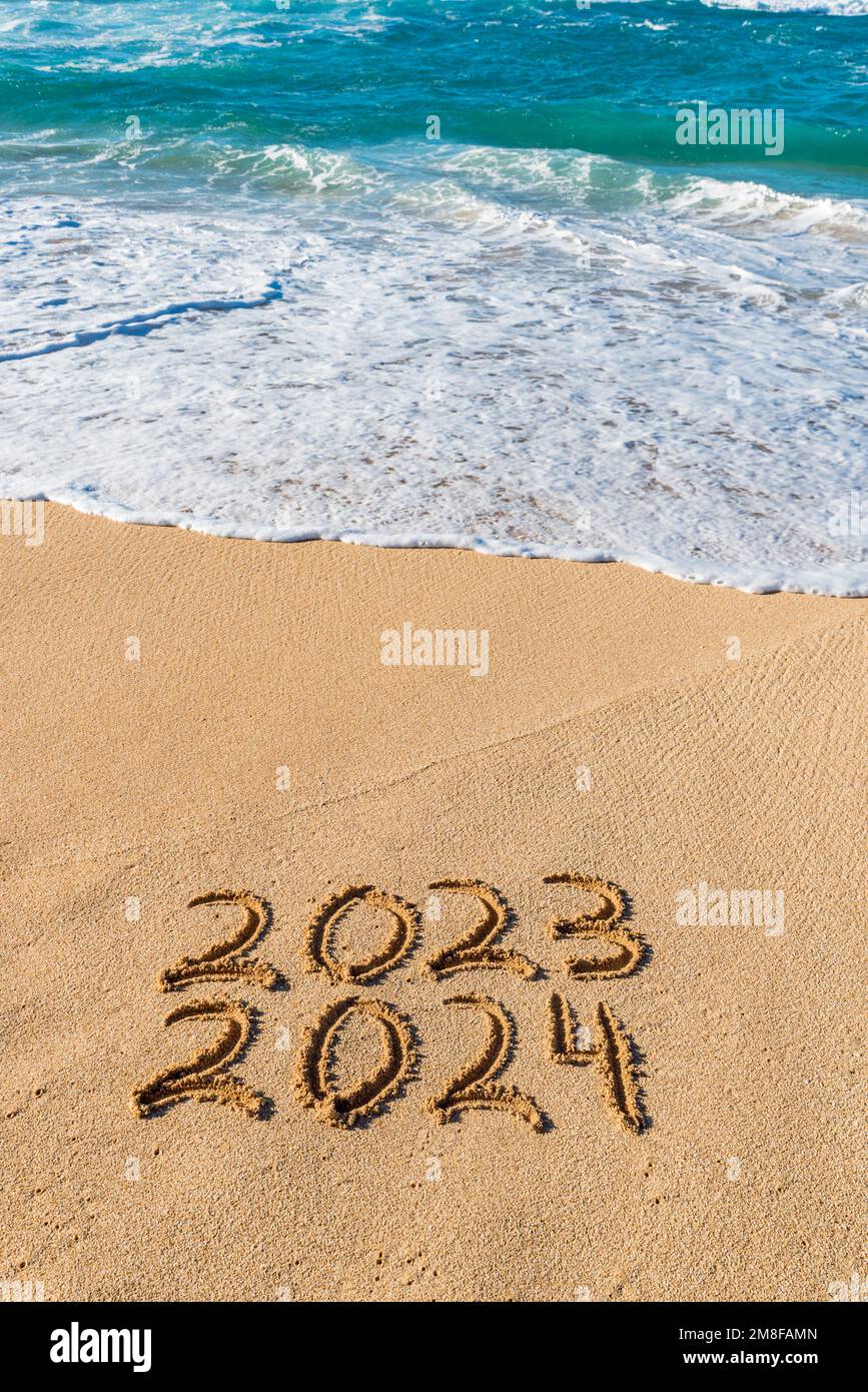 2023 2024 scritto nella sabbia con wave washing up-New Year Concept Foto Stock