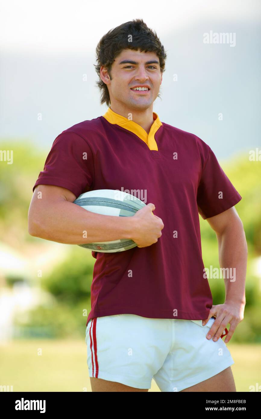 Felice di giocare. Ritratto ritagliato di un giovane giocatore di rugby che tiene una palla. Foto Stock