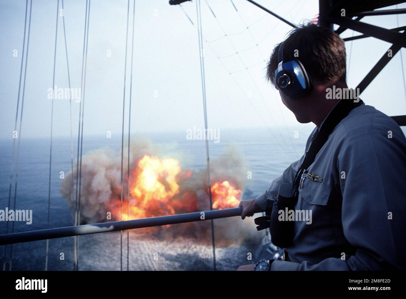 Un membro dell'equipaggio a bordo della nave da guerra USS WISCONSIN (BB-64) guarda come una delle pistole Mark 7 16-inch 50-calibro della nave è sparato. Questo è l'ultimo sparo di armi DEL WISCONSIN prima della sua disattivazione. Paese: Oceano Atlantico (AOC) Foto Stock