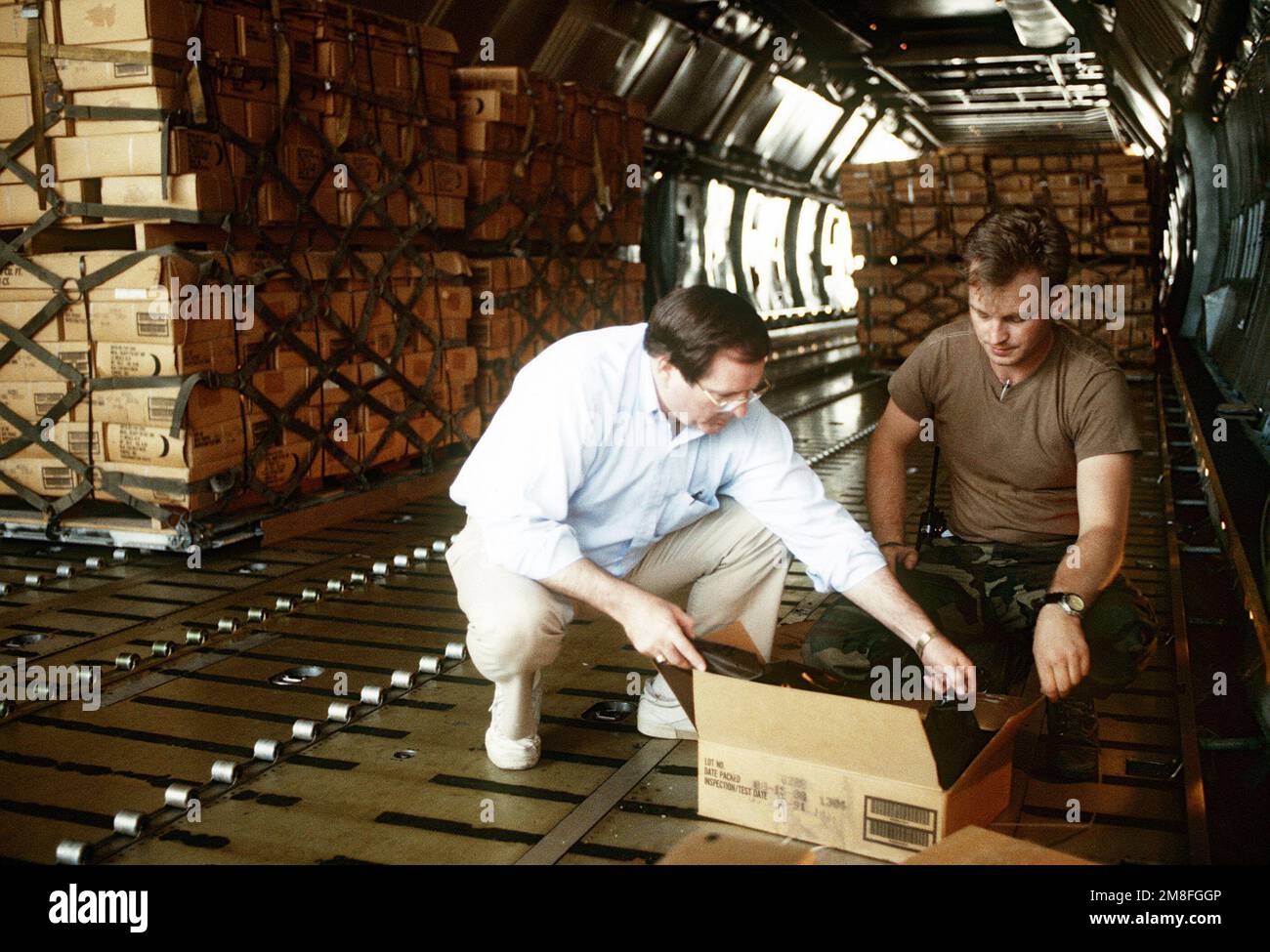 George Dykes, direttore dell'Ufficio di assistenza umanitaria, ispeziona una scatola di pasti pronti per il consumo (MREs) mentre vengono preparati per la spedizione ad Addis Abeba, Etiopia, dove la Croce Rossa li distribuirà ai rifugiati che soffrono a causa dei disordini civili di quel paese. Gli MREs sono forniture militari in eccesso e sono messi a disposizione dall'autorità del programma McCallum e del programma DOD Excess Property. Base: Dhahran Paese: Arabia Saudita(SAU) Foto Stock