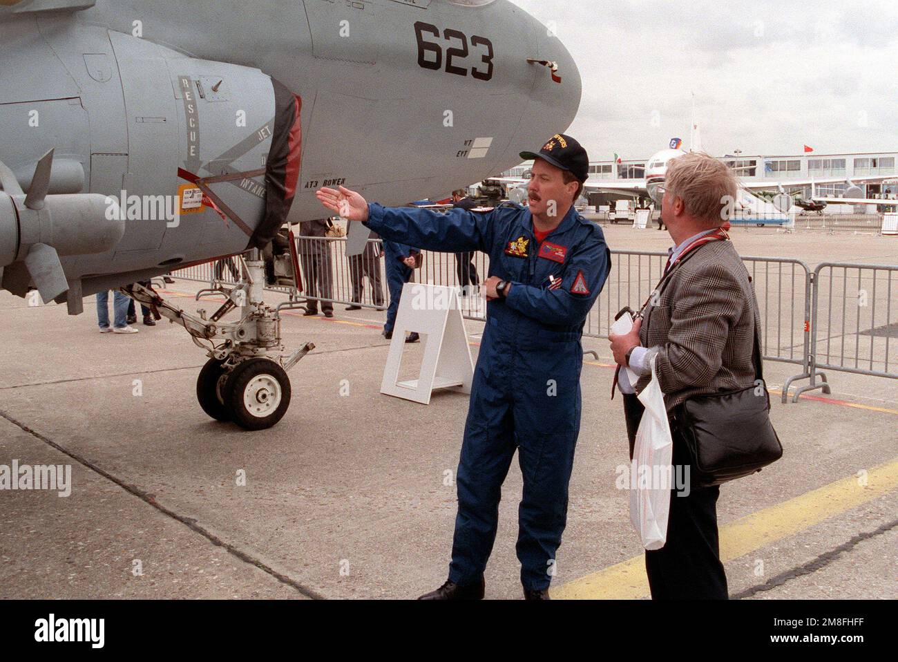 Un ufficiale di volo navale di Fighter Squadron 11 (VF-11) parla con un visitatore al Paris Air Show 1991. Dietro di loro c'è un Tactical Electronic Warfare Squadron 133 (VAQ-133) EA-6B Prowler Aircraft. Base: Paris Nazione: France(fra) Foto Stock