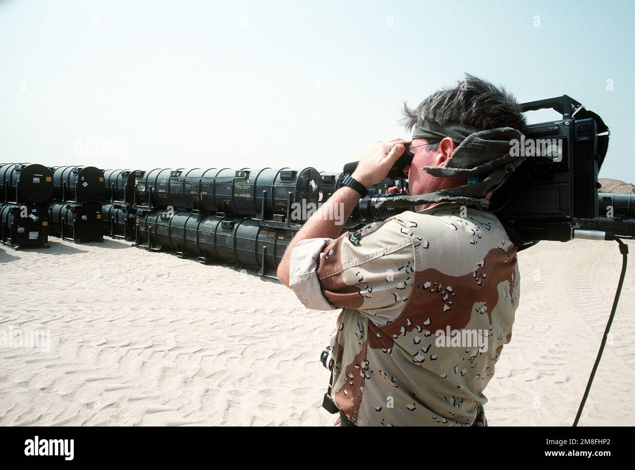Un video cameraman film ordignance contenitori a Ammo Supply Point 3 vicino Mishab. L'ordine e le attrezzature sono state caricate a bordo delle navi da carico militari Sealift Command Vehicle per la spedizione di ritorno negli Stati Uniti nel periodo successivo all'operazione Desert Storm. Soggetto operativo/Serie: TEMPESTA DEL DESERTO Paese: Arabia Saudita (SAU) Foto Stock