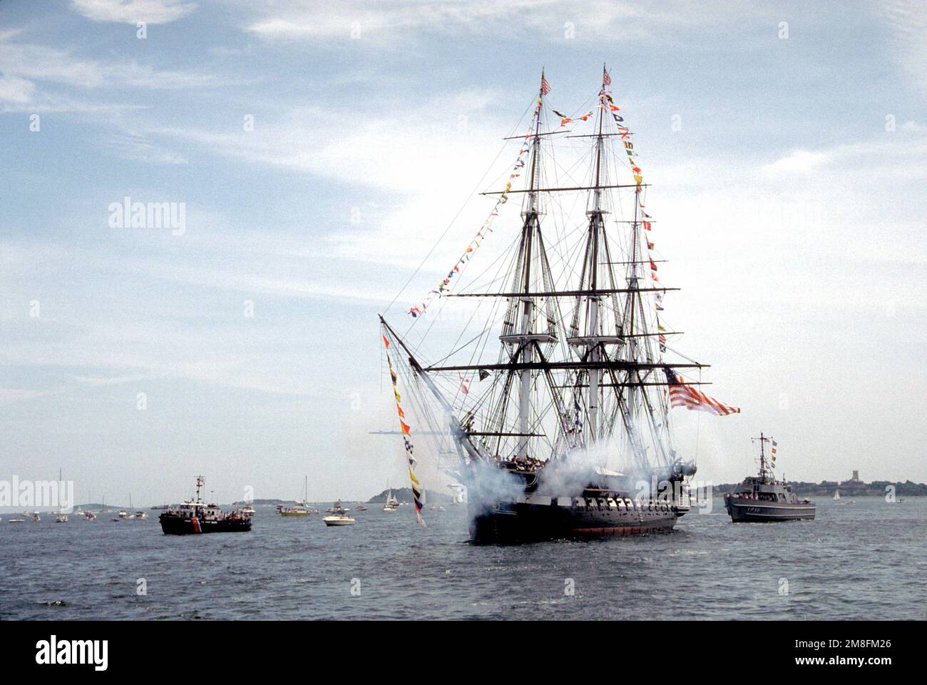 Il fumo si allontana dalla COSTITUZIONE USS della fregata a vela dopo il lancio di un saluto da 21 cannoni dalle lunghe pistole a 24 pozzi della nave durante la sua crociera annuale di ritorno. La COSTITUZIONE viene trainata nel porto ogni anno e riportata al suo ormeggio rivolto nella direzione opposta in modo che i suoi alberi non si piegino dagli effetti del sole e del vento. Base: Boston Stato: Massachusetts(ma) Paese: Stati Uniti d'America (USA) Foto Stock