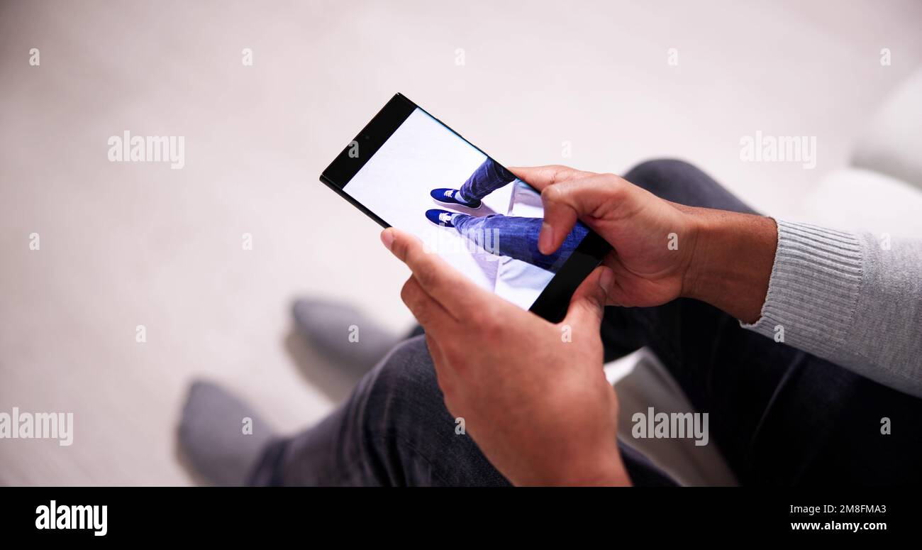 Uomo che prova Virtual Sneakers in negozio o app Store AR Foto Stock