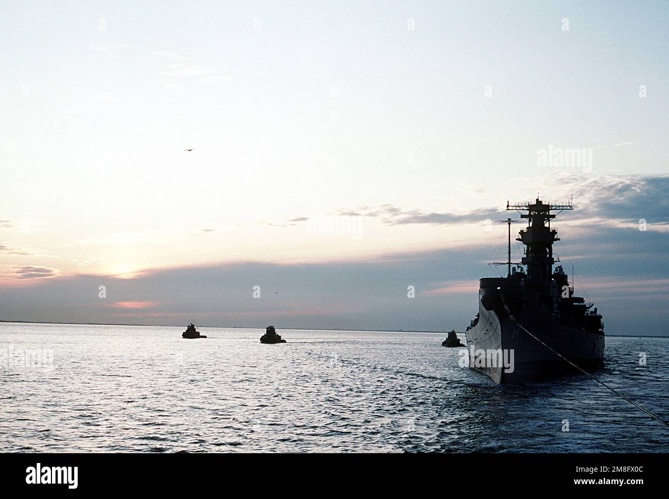 Tre rimorchiatori seguono la nave da guerra SMANTELLATA WISCONSIN (BB-64) mentre viene trainata al cantiere navale di Philadelphia, Pennsylvania. Paese: Sconosciuto Foto Stock